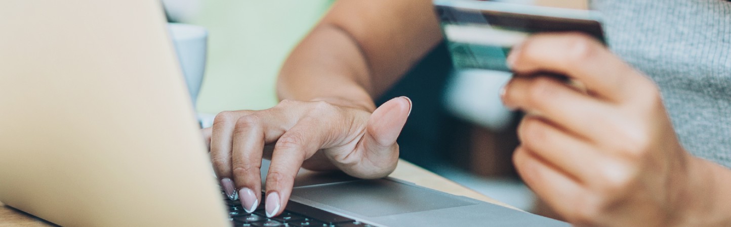 Mujer escribiendo los datos de su tarjeta de crédito en un computador