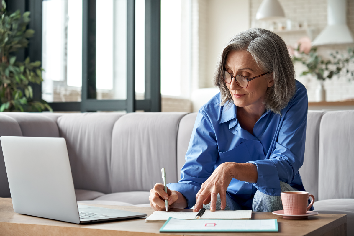 Mujer escribiendo a mano frente a computador