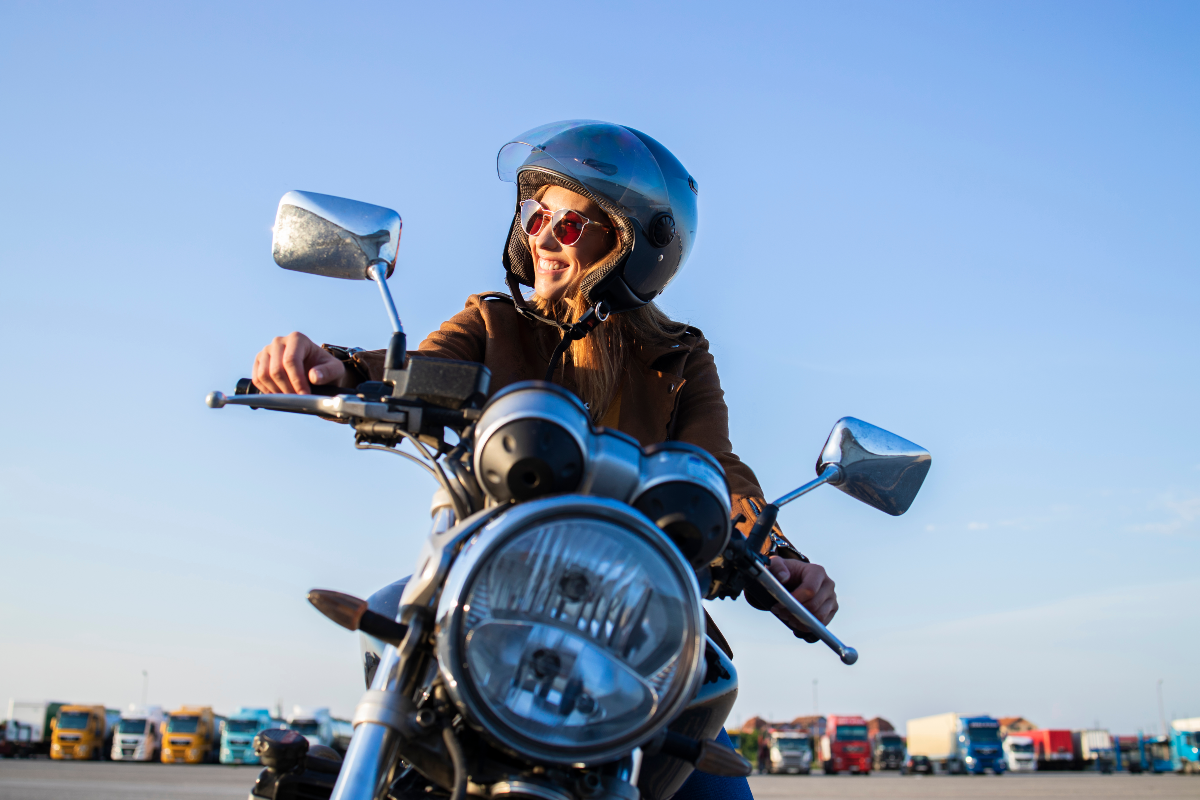 Mujer motociclista sonriendo al sol