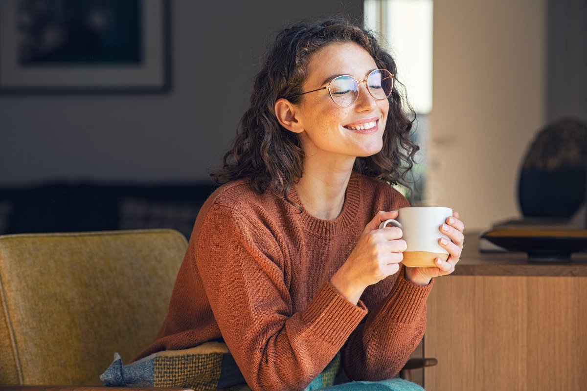 Mujer tomando una bebida caliente y sonriendo