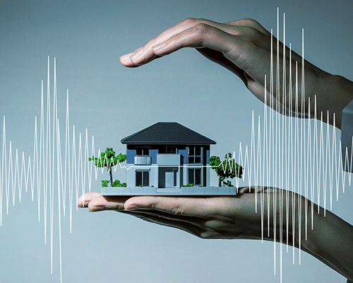 Vivienda protegida entre dos manos como símbolo de las coberturas y el acompañamiento de un seguro después de un sismo